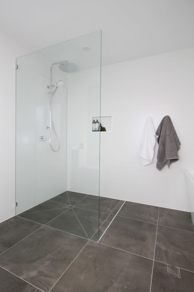 Photo of a mid-sized contemporary master bathroom in Brisbane with flat-panel cabinets, light wood cabinets, a freestanding tub, an open shower, a two-piece toilet, white tile, ceramic tile, white walls, porcelain floors, a vessel sink, engineered quartz benchtops, grey floor, an open shower and white benchtops.
