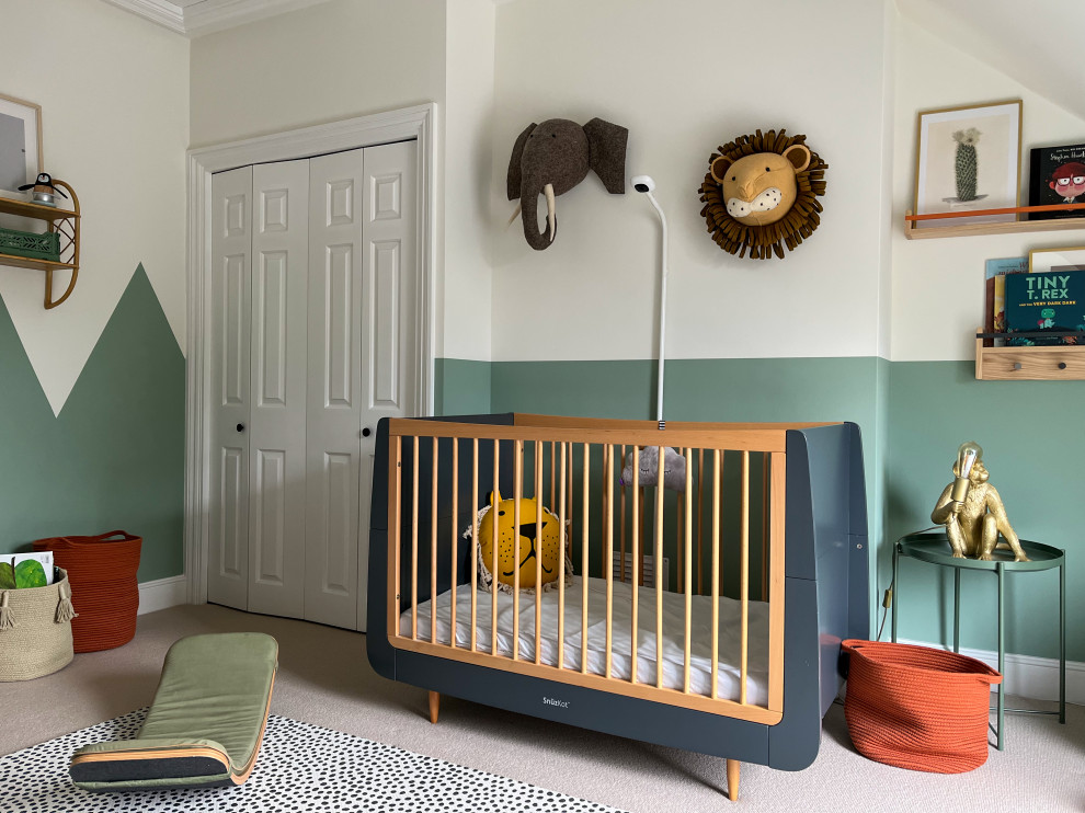 Mid-sized modern gender-neutral nursery in London with green walls, carpet, beige floor and wallpaper.