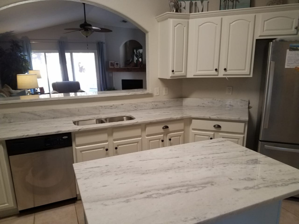 Kitchen - kitchen idea with white cabinets, stainless steel appliances, an island and white countertops