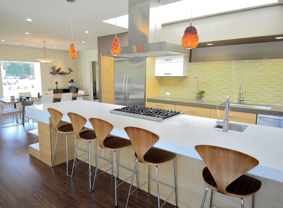 Photo of a large midcentury galley eat-in kitchen in San Francisco with stainless steel appliances, yellow splashback, glass tile splashback, light wood cabinets, flat-panel cabinets, an undermount sink, quartz benchtops, dark hardwood floors, with island and brown floor.