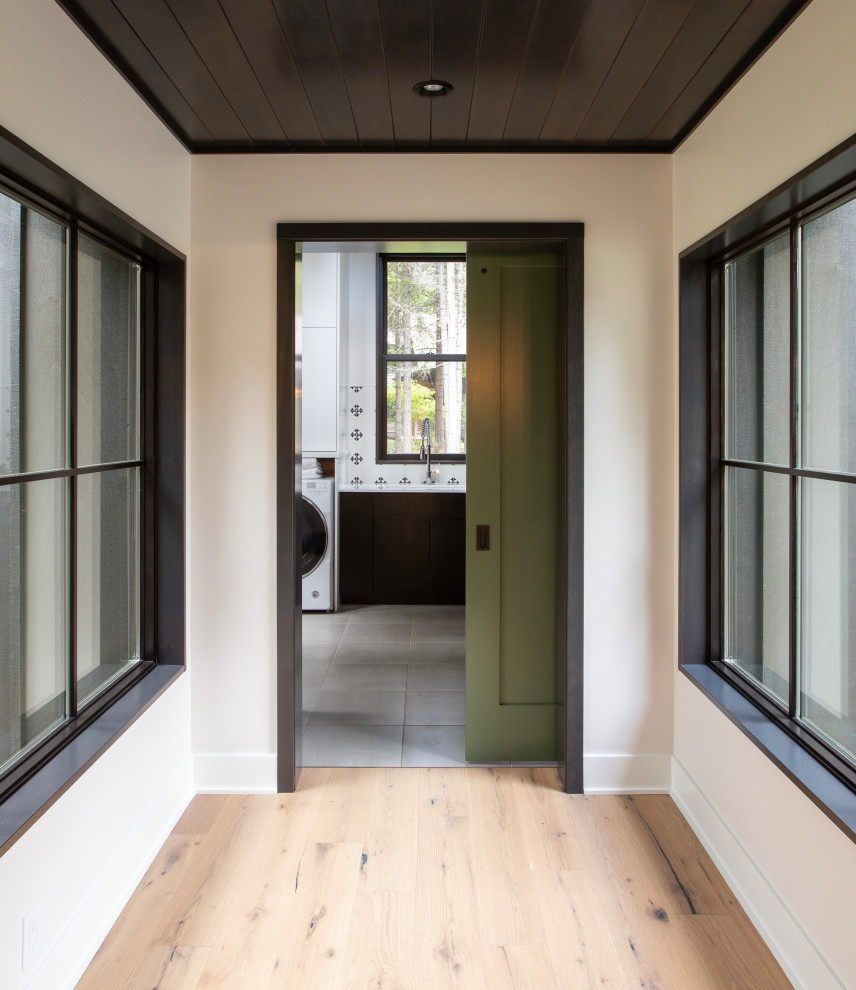 Cette image montre un couloir minimaliste de taille moyenne avec un mur blanc, parquet clair, un sol marron et un plafond en bois.