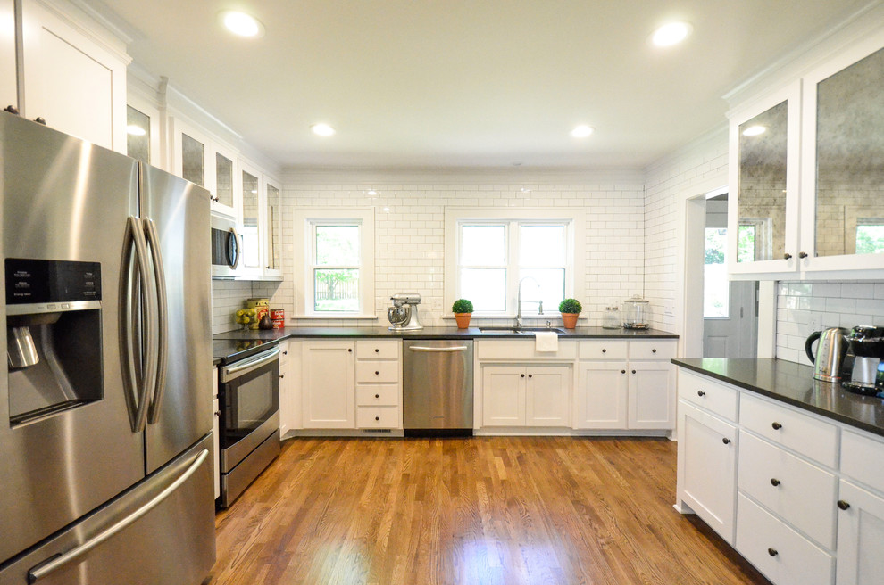 Eat-in kitchen - large transitional l-shaped light wood floor and brown floor eat-in kitchen idea in Kansas City with an undermount sink, shaker cabinets, white cabinets, quartz countertops, white backsplash, subway tile backsplash, stainless steel appliances, no island and gray countertops