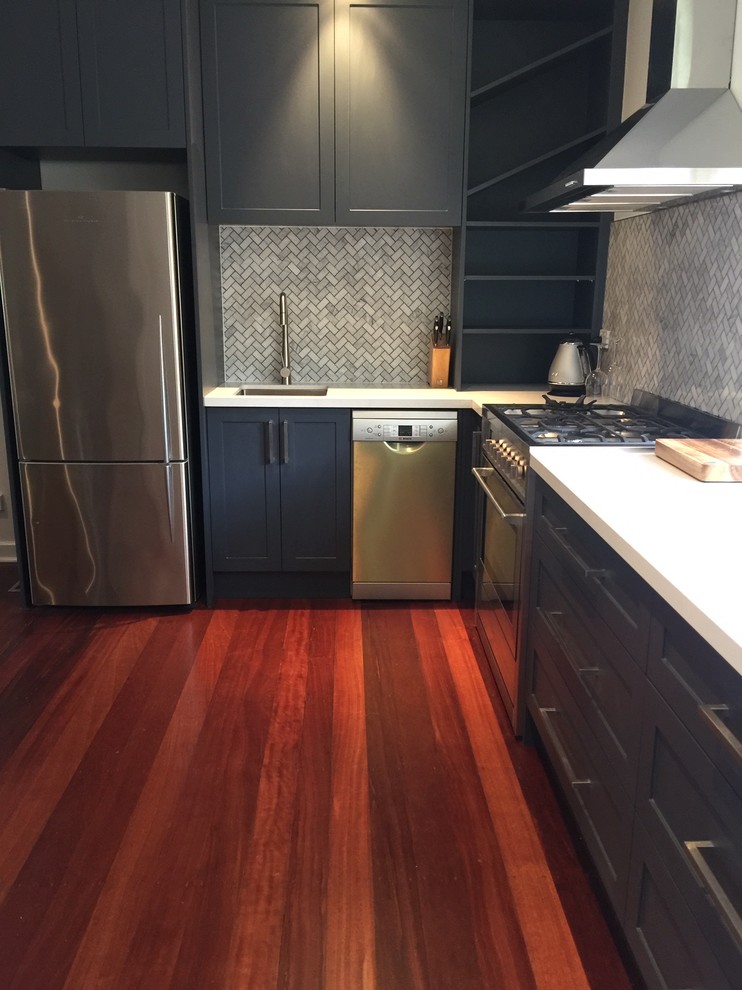 Design ideas for a small contemporary l-shaped eat-in kitchen in Melbourne with an undermount sink, shaker cabinets, grey cabinets, quartz benchtops, grey splashback, mosaic tile splashback, stainless steel appliances, medium hardwood floors, red floor, white benchtop and no island.