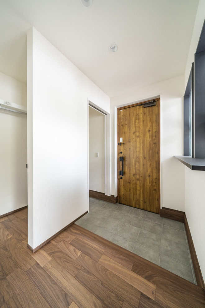 Photo of a mid-sized modern entry hall in Other with white walls, dark hardwood floors, a single front door, a light wood front door, brown floor, wallpaper and wallpaper.