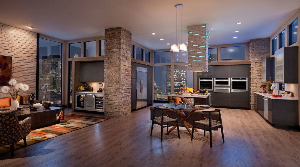 Mid-sized modern l-shaped open plan kitchen in Philadelphia with flat-panel cabinets, grey cabinets, stainless steel appliances, medium hardwood floors, with island and beige floor.