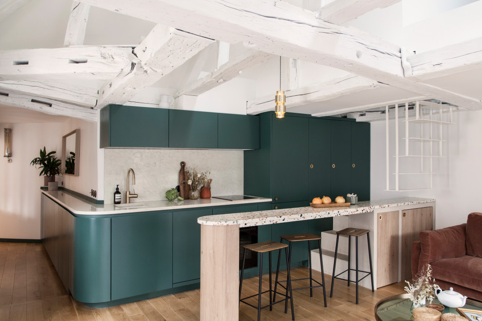 Inspiration for a contemporary galley kitchen in Paris with an undermount sink, flat-panel cabinets, green cabinets, beige splashback, panelled appliances, medium hardwood floors, a peninsula, brown floor and beige benchtop.