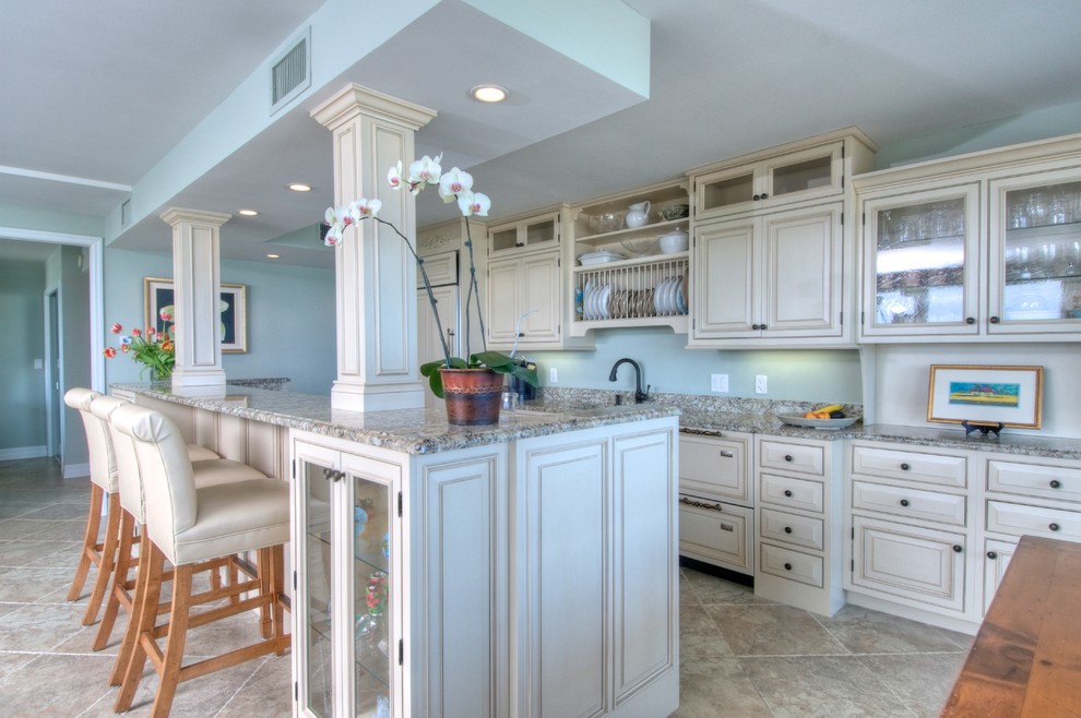 This is an example of a large traditional galley kitchen in Tampa with raised-panel cabinets, beige cabinets, with island, an undermount sink, granite benchtops, panelled appliances, ceramic floors, beige floor and multi-coloured benchtop.