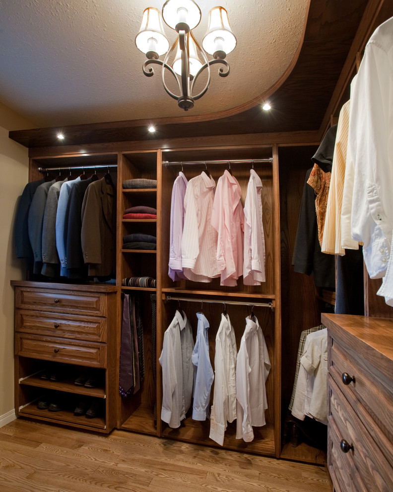 Inspiration for a large traditional men's walk-in wardrobe in Calgary with raised-panel cabinets, medium wood cabinets and medium hardwood floors.