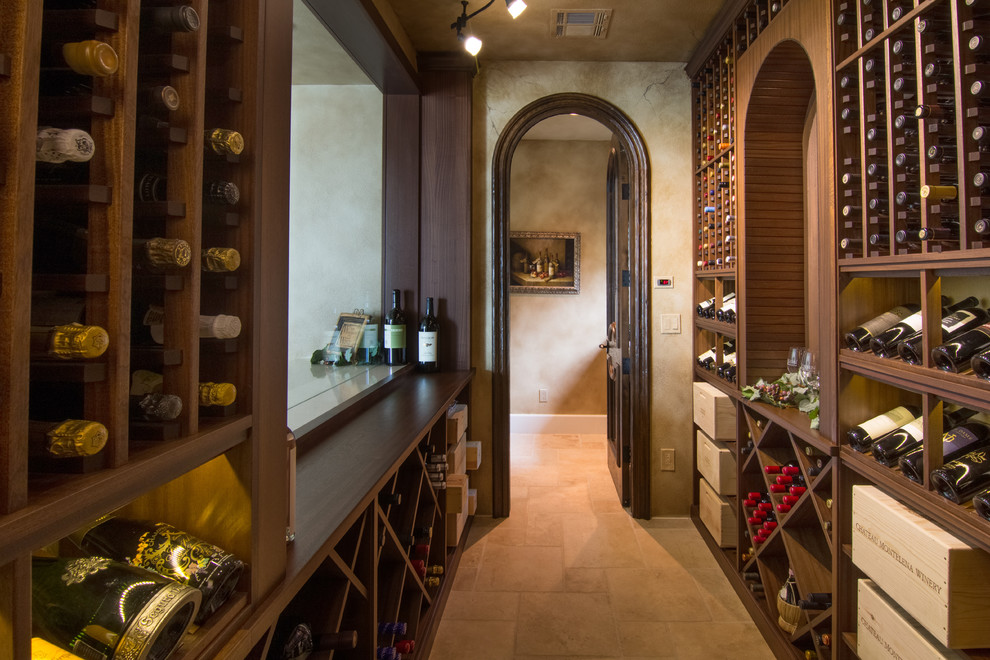 This is an example of a mid-sized traditional wine cellar in Los Angeles with storage racks and beige floor.