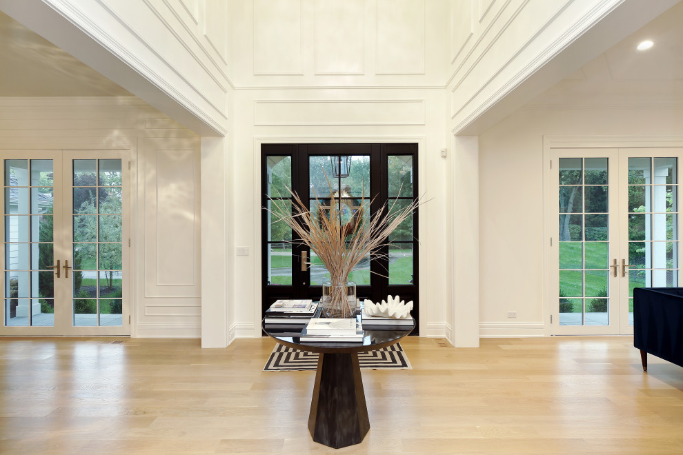 Foyer - large transitional light wood floor foyer idea in Chicago with white walls and a glass front door