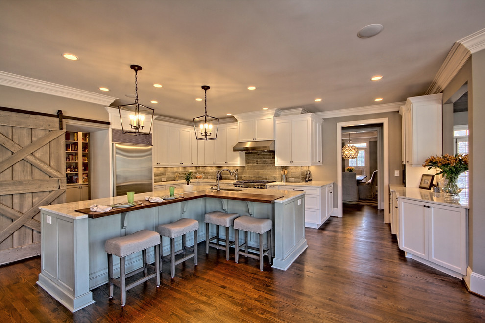 This is an example of a country l-shaped kitchen in Atlanta with shaker cabinets, white cabinets, marble benchtops, porcelain splashback, stainless steel appliances, dark hardwood floors, with island, an undermount sink and grey splashback.