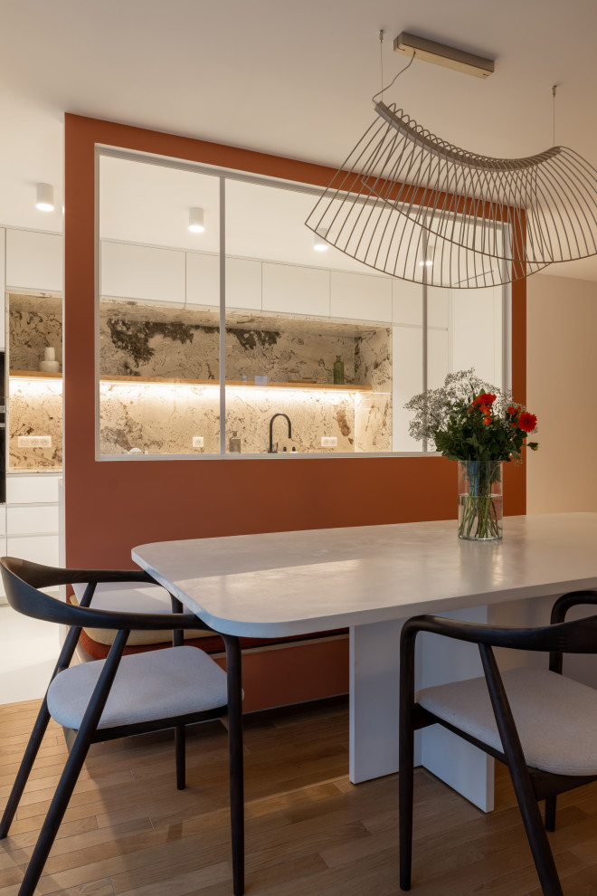 Immagine di una grande sala da pranzo contemporanea con pareti arancioni, parquet chiaro e pavimento marrone