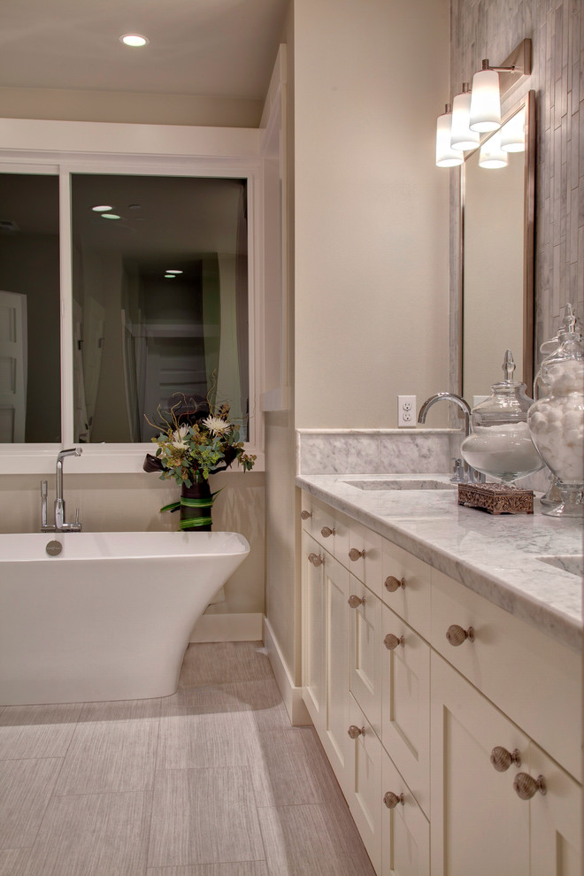 Large contemporary master bathroom in Seattle with an undermount sink, shaker cabinets, white cabinets, marble benchtops, a freestanding tub, white tile, stone tile, ceramic floors and grey walls.