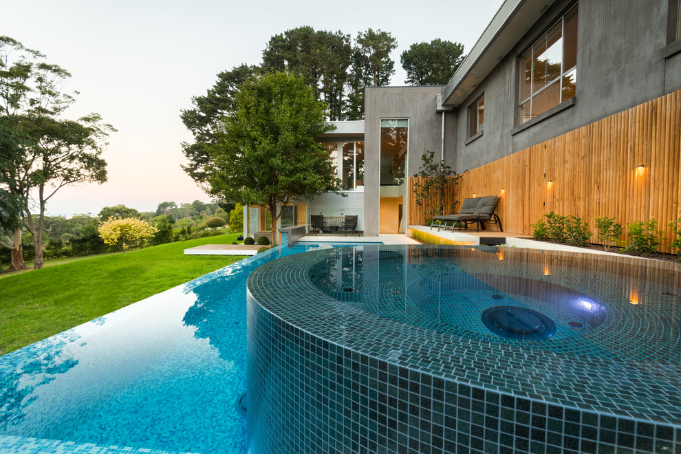 Large contemporary backyard custom-shaped infinity pool in Melbourne with a hot tub and concrete slab.