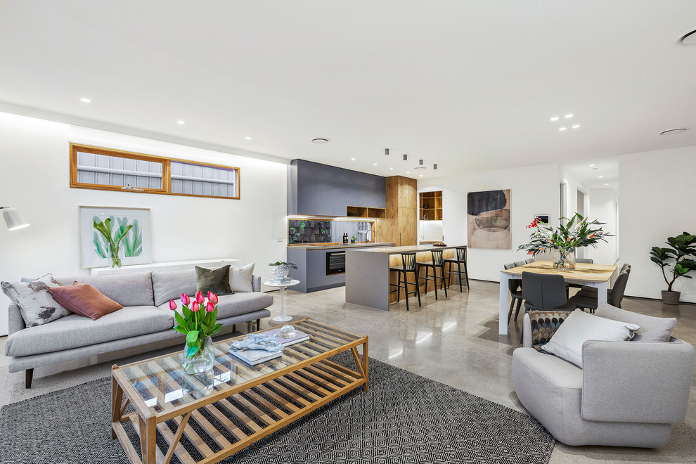 This is an example of a mid-sized contemporary open concept living room in Melbourne with white walls, concrete floors, no fireplace, a wall-mounted tv and grey floor.