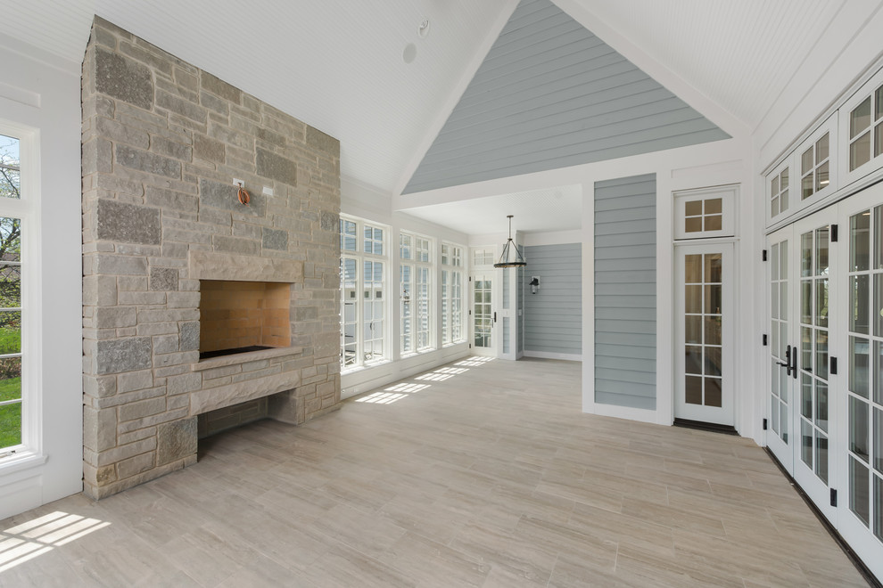 Photo of a large transitional sunroom in Chicago with ceramic floors, a standard fireplace, a stone fireplace surround, a standard ceiling and grey floor.