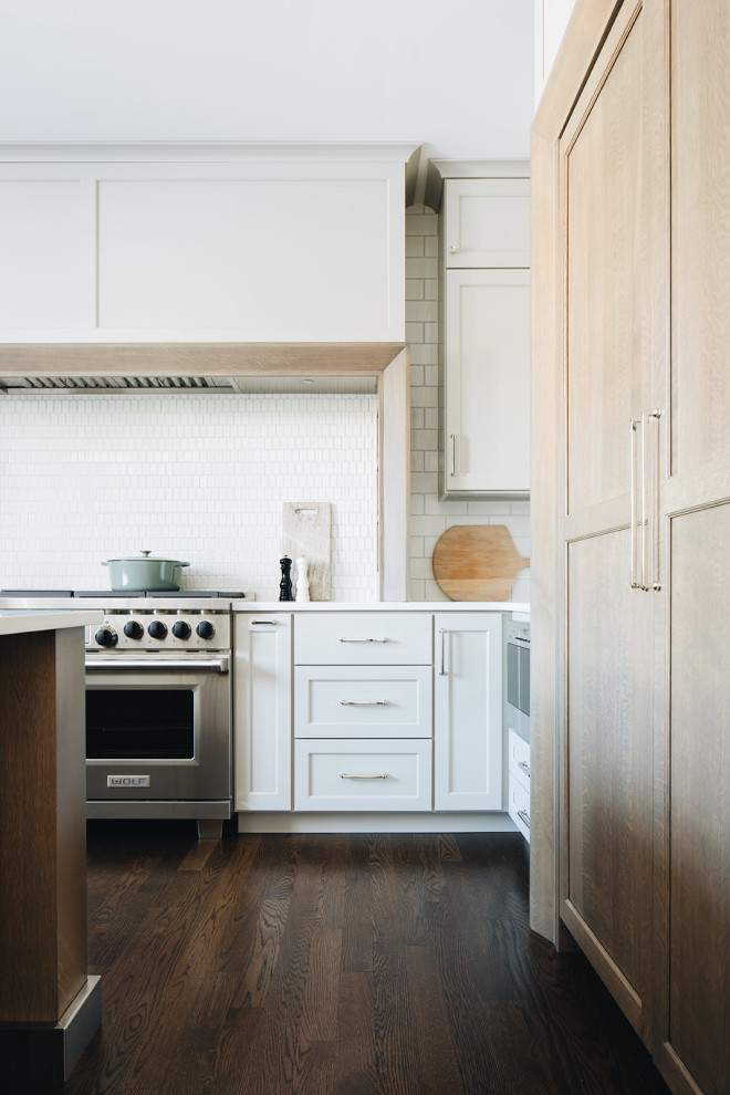 Example of a mid-sized transitional dark wood floor eat-in kitchen design in Chicago with a farmhouse sink, shaker cabinets, gray cabinets, quartz countertops, white backsplash, ceramic backsplash, paneled appliances, an island and white countertops