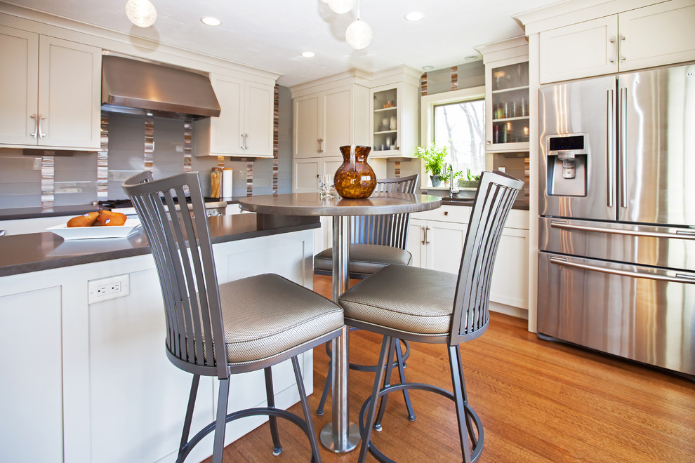 Large transitional l-shaped medium tone wood floor eat-in kitchen photo in Boston with an undermount sink, shaker cabinets, white cabinets, quartz countertops, gray backsplash, glass sheet backsplash, stainless steel appliances and an island