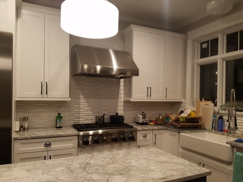 This is an example of a mid-sized traditional l-shaped eat-in kitchen in Chicago with a farmhouse sink, shaker cabinets, white cabinets, quartzite benchtops, white splashback, ceramic splashback, stainless steel appliances, medium hardwood floors and with island.