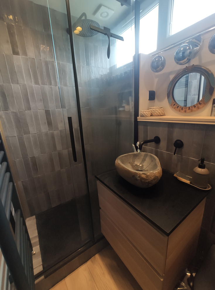Inredning av ett litet svart svart badrum med dusch, med beige skåp, en dusch i en alkov, en vägghängd toalettstol, grå kakel, beige väggar, ljust trägolv, ett konsol handfat, beiget golv och dusch med skjutdörr
