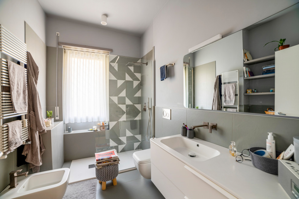 Photo of a large modern 3/4 bathroom in Rome with white cabinets, an open shower, gray tile, porcelain tile, grey walls, porcelain floors, an integrated sink, grey floor, white benchtops, a single vanity, a floating vanity and solid surface benchtops.