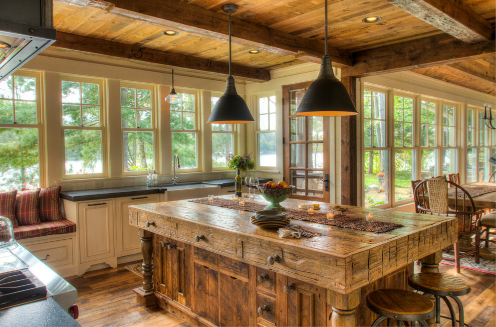 Design ideas for a large country l-shaped eat-in kitchen in Minneapolis with a farmhouse sink, beaded inset cabinets, white cabinets, soapstone benchtops, white splashback, dark hardwood floors, with island, brown floor and black benchtop.