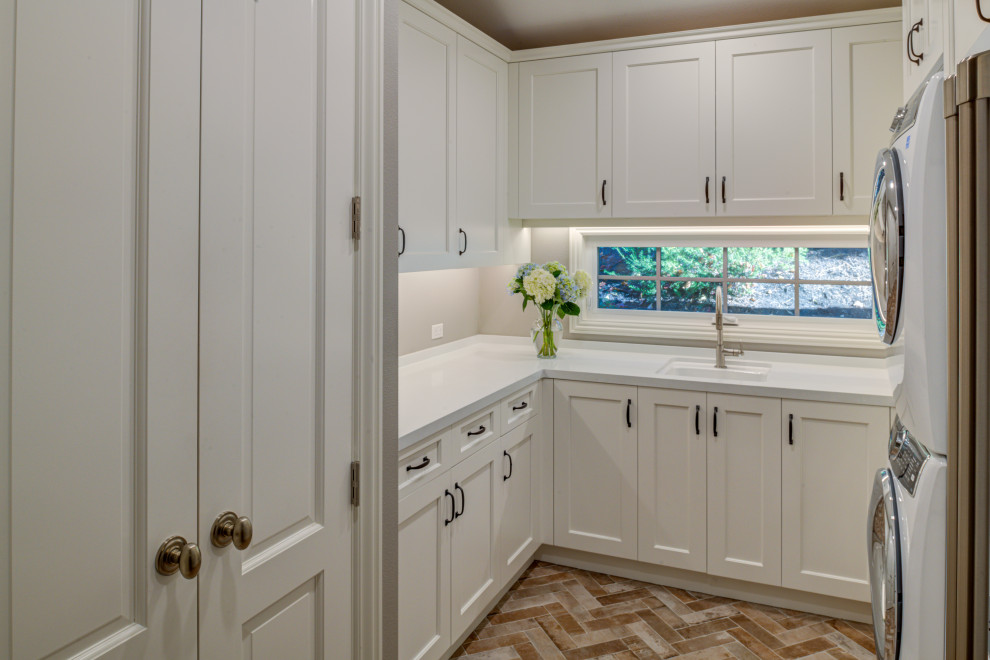 Design ideas for a small classic u-shaped separated utility room in San Francisco with a submerged sink, recessed-panel cabinets, white cabinets, engineered stone countertops, grey walls, porcelain flooring, a stacked washer and dryer, orange floors and white worktops.