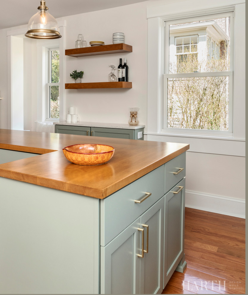 Photo of a mid-sized country l-shaped separate kitchen in Philadelphia with a farmhouse sink, shaker cabinets, green cabinets, quartz benchtops, white splashback, subway tile splashback, stainless steel appliances, medium hardwood floors, with island, brown floor and white benchtop.