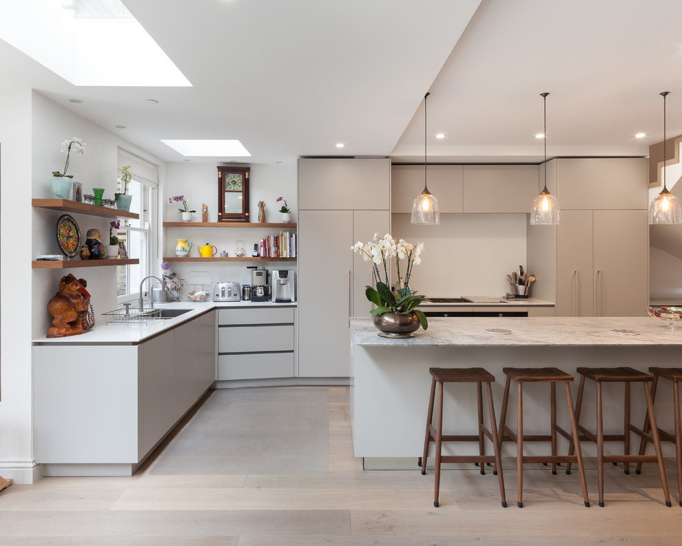 This is an example of a mid-sized contemporary l-shaped kitchen in London with a double-bowl sink, flat-panel cabinets, grey cabinets, marble benchtops, light hardwood floors, with island and grey floor.