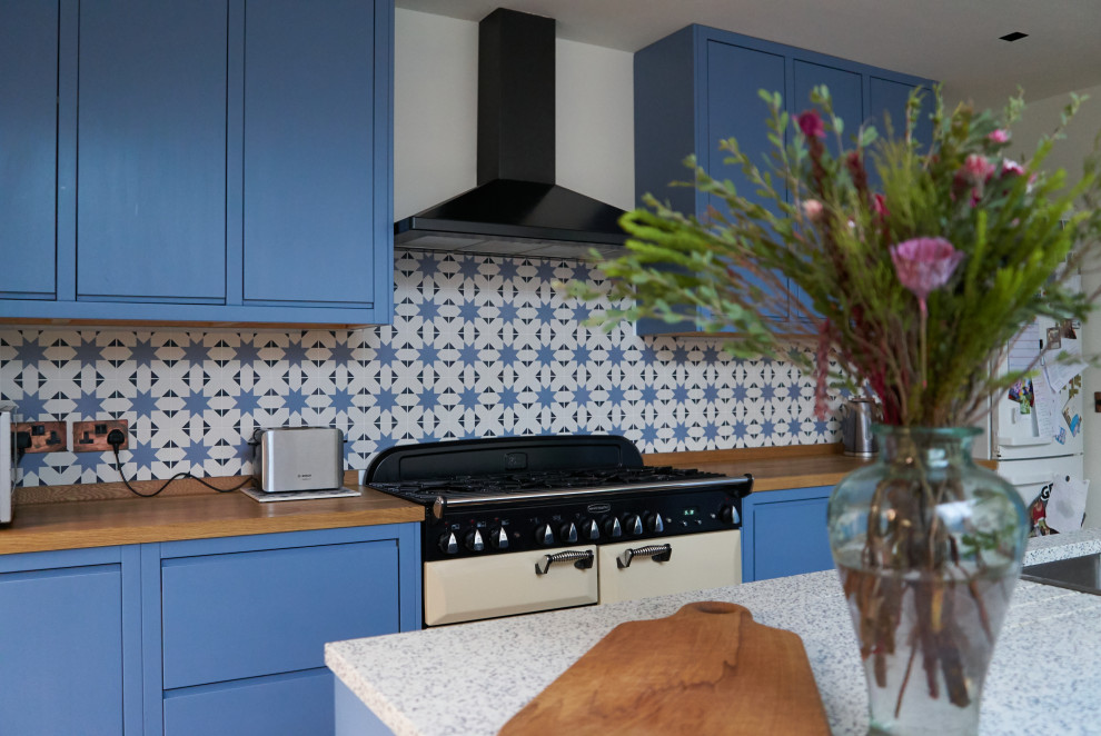 Inspiration för ett stort funkis blå blått kök, med en integrerad diskho, släta luckor, blå skåp, bänkskiva i återvunnet glas, blått stänkskydd, stänkskydd i porslinskakel, vita vitvaror, ljust trägolv och en köksö