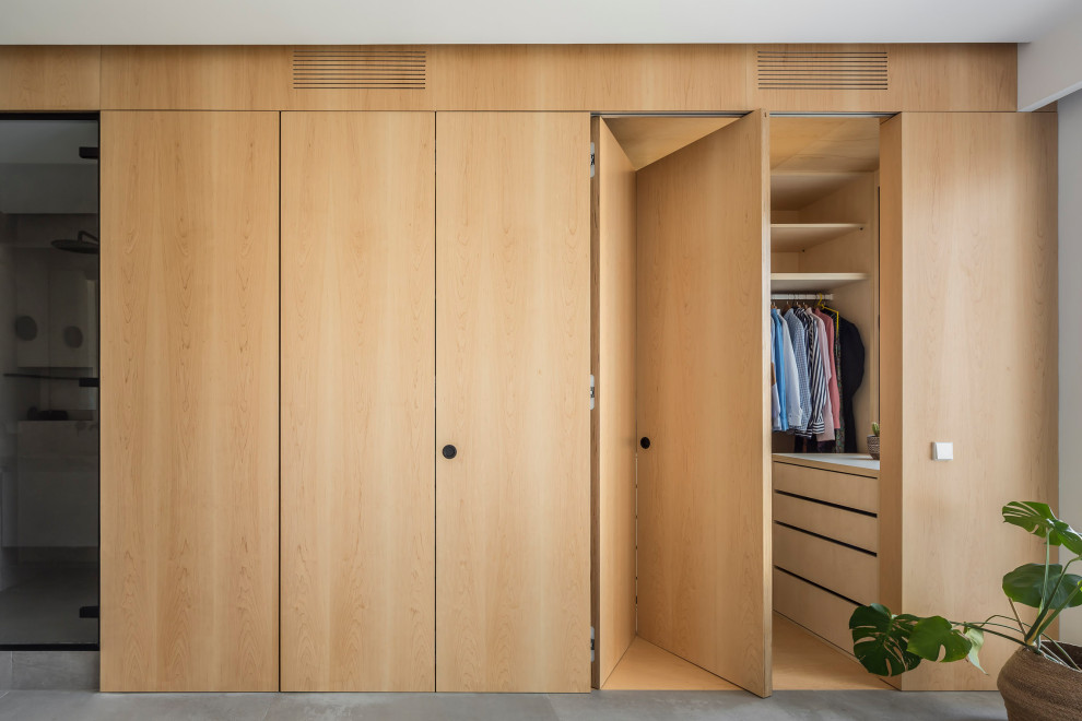 Photo of a mid-sized contemporary gender-neutral walk-in wardrobe in Valencia with recessed-panel cabinets, medium wood cabinets, ceramic floors and grey floor.