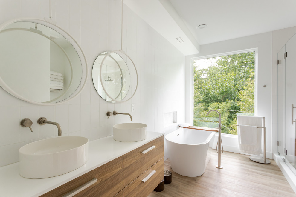This is an example of a mid-sized contemporary kids bathroom in Philadelphia with white cabinets, a freestanding tub, a double shower, white floor, a hinged shower door, white benchtops, an enclosed toilet, a double vanity, a built-in vanity, flat-panel cabinets, laminate floors, a trough sink and laminate benchtops.