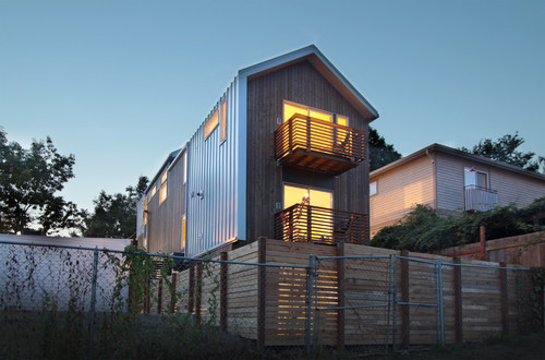 This modern home has a large horizontal slat wooden privacy fence around the main outdoor backyard living area, but uses a tall chain link fence to secure the boundaries of the rest of the property.