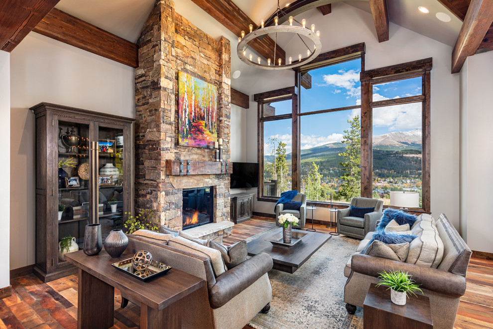 Living room - rustic medium tone wood floor and brown floor living room idea in Denver with gray walls, a standard fireplace, a stone fireplace and a wall-mounted tv