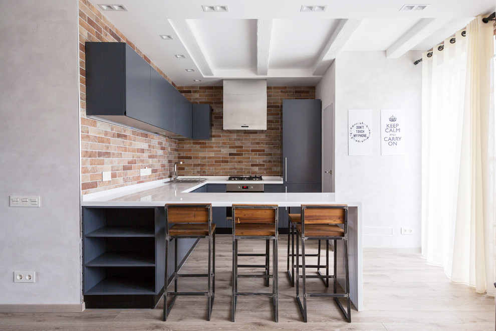 Photo of a contemporary l-shaped kitchen in London with a drop-in sink, flat-panel cabinets, grey cabinets, brown splashback, stainless steel appliances, medium hardwood floors and a peninsula.