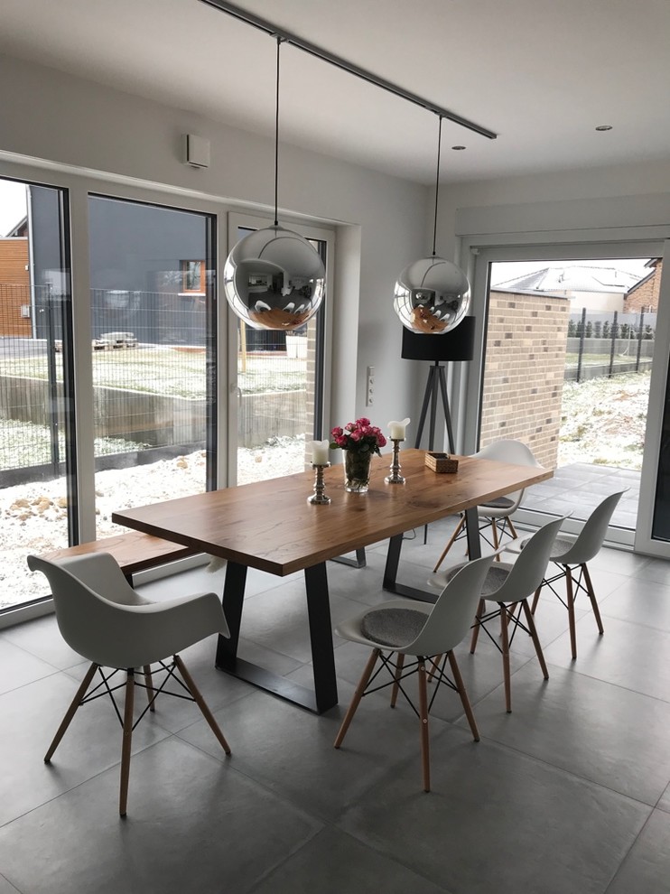 Mid-sized modern separate dining room in Cologne with white walls, no fireplace and grey floor.