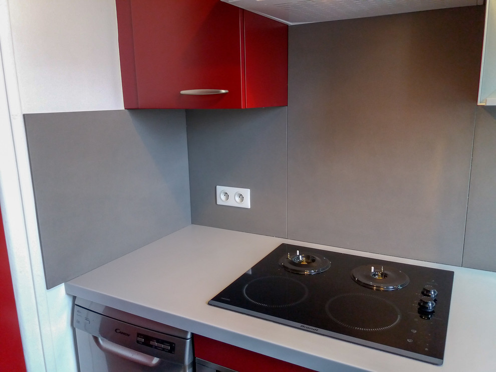 Inspiration for a mid-sized modern l-shaped eat-in kitchen in Paris with an integrated sink, flat-panel cabinets, red cabinets, solid surface benchtops, grey splashback, stone slab splashback, stainless steel appliances, vinyl floors, with island, grey floor and grey benchtop.