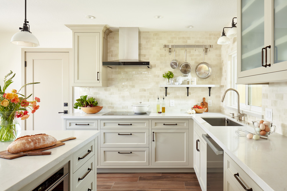 Inspiration for a transitional l-shaped kitchen in San Francisco with an undermount sink, recessed-panel cabinets, beige cabinets, beige splashback, stainless steel appliances, with island, brown floor and white benchtop.