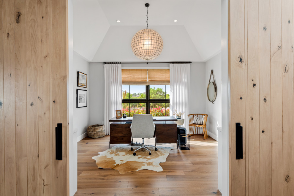 This is an example of an expansive home office in Los Angeles with grey walls, light hardwood floors, a freestanding desk, beige floor and vaulted.