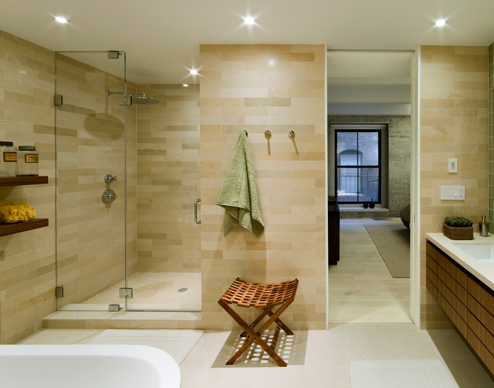 Inspiration for a modern bathroom in New York with medium wood cabinets, beige tile, an undermount sink, an alcove shower and a freestanding tub.