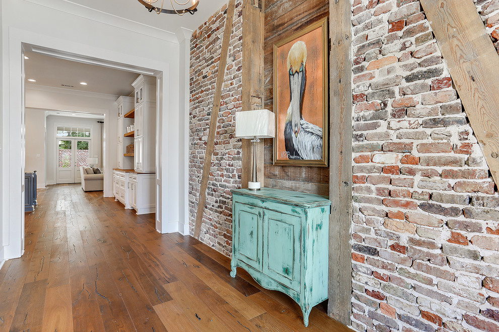 This is an example of a mid-sized country entry hall in New Orleans with red walls, dark hardwood floors, a single front door and brown floor.