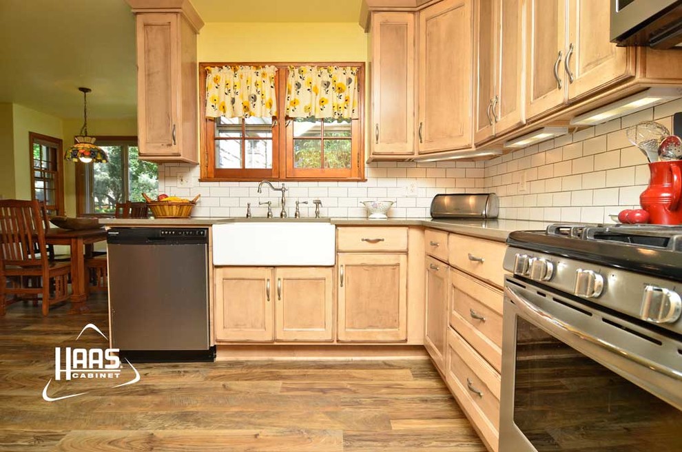 Exempel på ett mellanstort lantligt kök, med en rustik diskho, luckor med infälld panel, skåp i ljust trä, vitt stänkskydd, stänkskydd i tunnelbanekakel, rostfria vitvaror och mellanmörkt trägolv