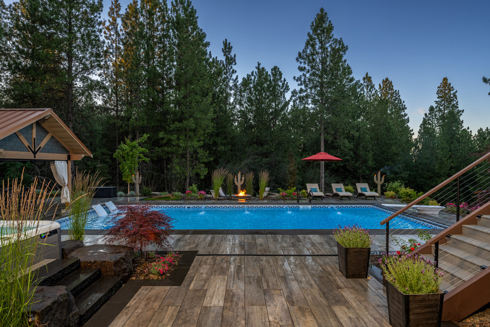 Ispirazione per un'ampia piscina monocorsia stile americano rettangolare dietro casa con paesaggistica bordo piscina e pavimentazioni in pietra naturale