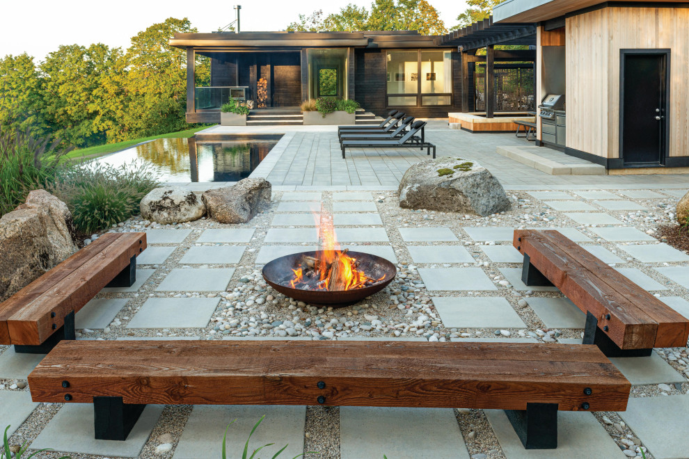 This is an example of a country backyard patio in Other with a fire feature, concrete slab and a pergola.