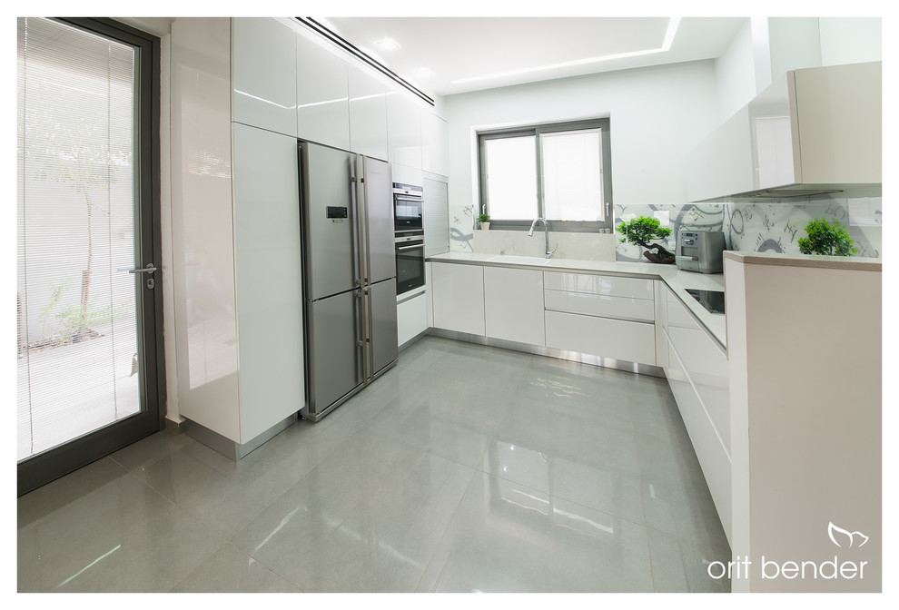 This is an example of a medium sized contemporary kitchen pantry in Tel Aviv with a single-bowl sink, white cabinets, marble worktops, white splashback, glass sheet splashback, stainless steel appliances, ceramic flooring and an island.