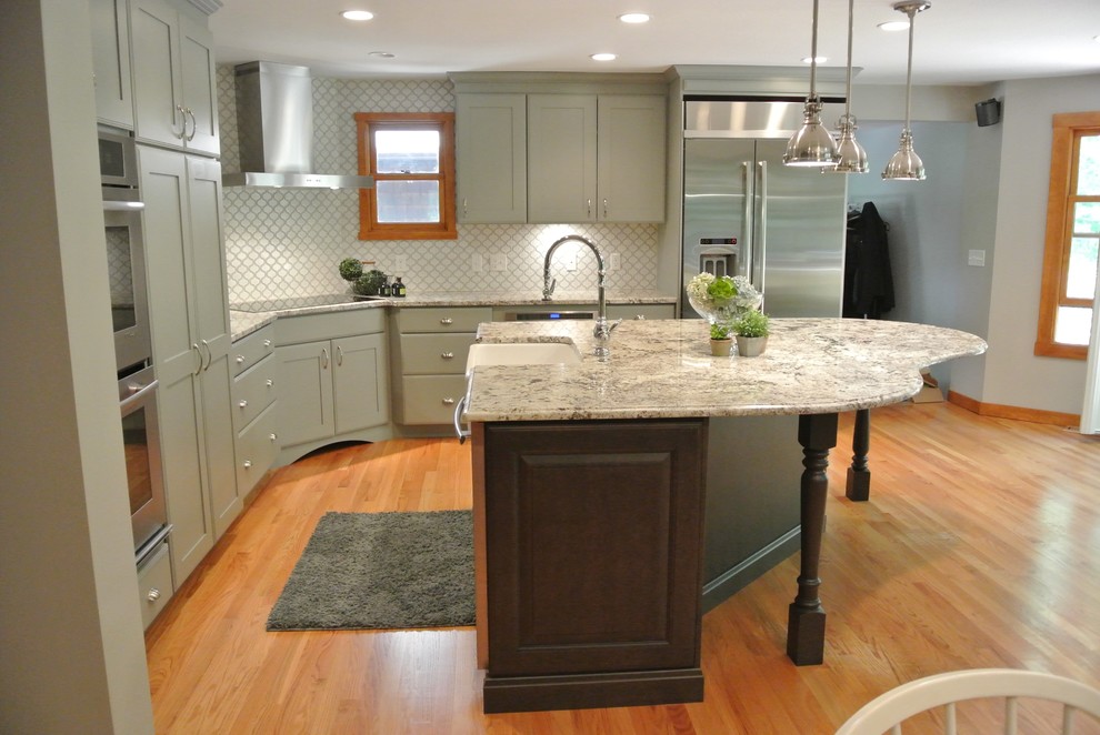 Large transitional l-shaped light wood floor eat-in kitchen photo in Boston with a farmhouse sink, shaker cabinets, gray cabinets, granite countertops, white backsplash, ceramic backsplash, stainless steel appliances, an island and gray countertops