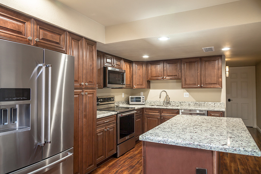 Enclosed kitchen - mid-sized transitional l-shaped laminate floor and brown floor enclosed kitchen idea in Phoenix with an undermount sink, shaker cabinets, medium tone wood cabinets, granite countertops, multicolored backsplash, stone slab backsplash, stainless steel appliances and an island