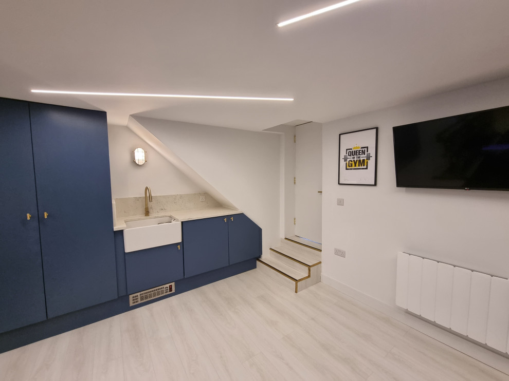 Photo of a mid-sized contemporary multipurpose gym in London with white walls, laminate floors, multi-coloured floor and recessed.