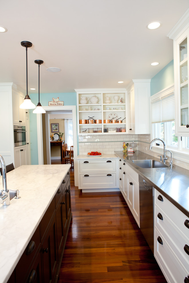Design ideas for a country kitchen in Seattle with an integrated sink, shaker cabinets, white cabinets, stainless steel benchtops, white splashback, subway tile splashback and stainless steel appliances.
