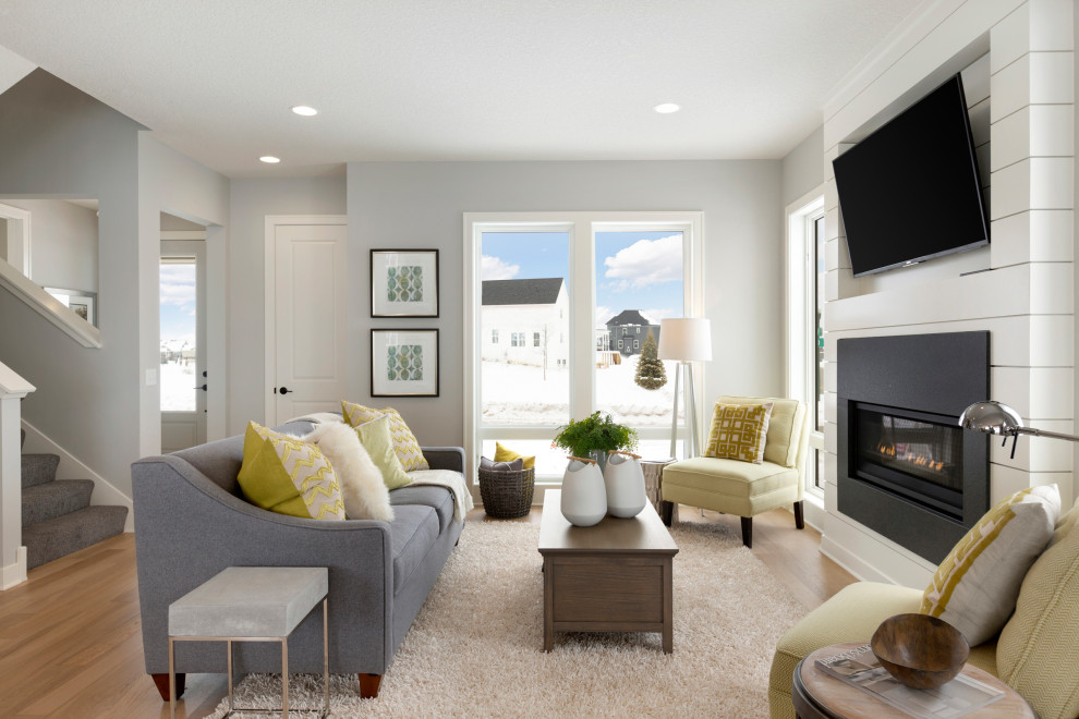 Photo of a transitional open concept living room in Minneapolis with grey walls, light hardwood floors, a standard fireplace and a wall-mounted tv.